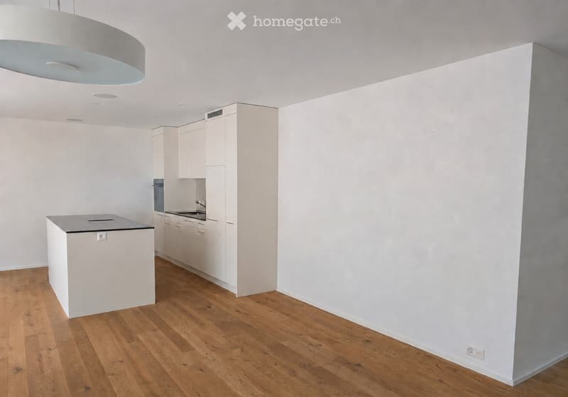 Modern kitchen with white cabinets, a central island, and wooden flooring.