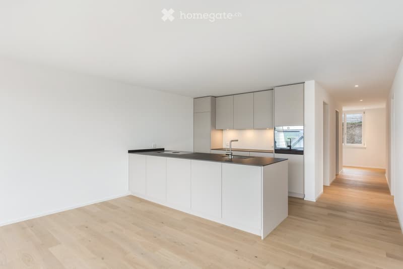 Modern, minimalist kitchen with white cabinets, a black countertop, and a central island. Features include a sink with a modern faucet, an oven, and ample storage space.