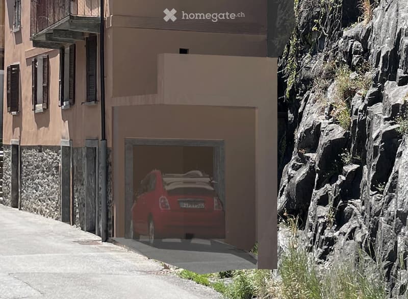 A two-story building with a visible garage entrance, a red car parked inside, and a rocky hillside to the right.