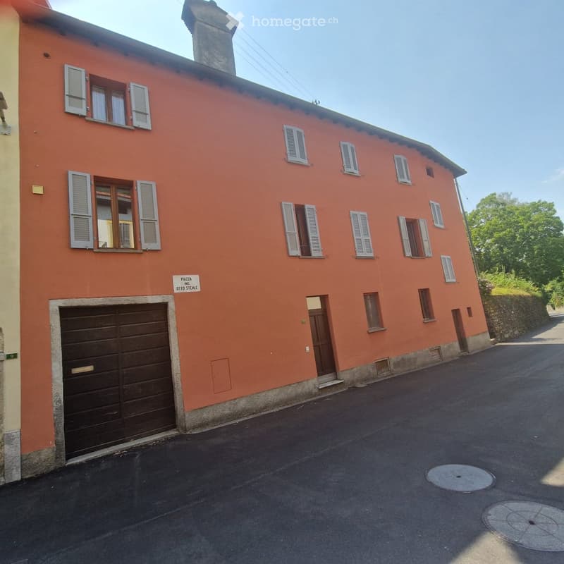 Two-story orange house with multiple windows, shutters, and a garage door on the ground floor.