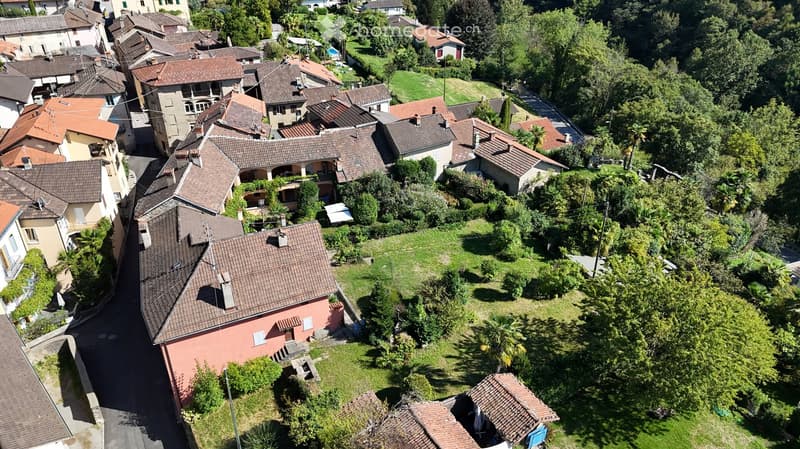 Aerial view of a residential area with multiple houses, tiled roofs, and surrounding greenery.