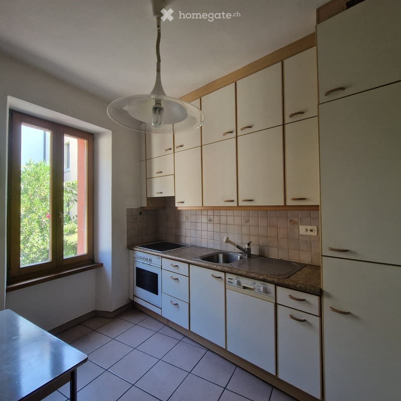 Modern kitchen with white cabinets, tiled backsplash, stainless steel sink, and built-in appliances including an oven and dishwasher.