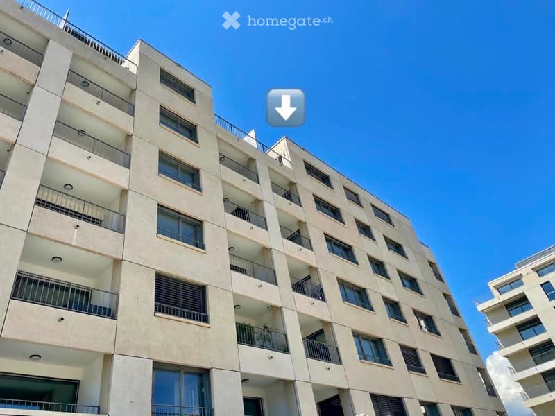 Modern multi-story residential building with balconies and large windows under a clear blue sky.