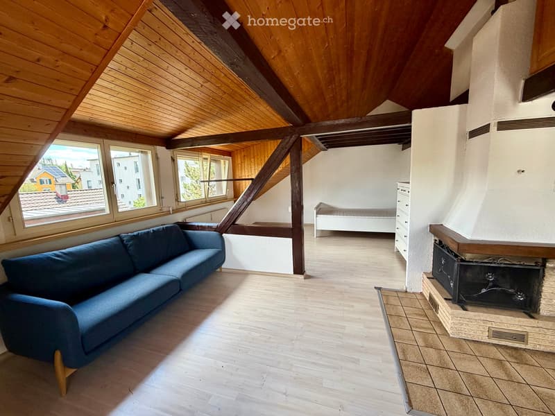 Living room with wooden ceiling beams, exposed wooden beams, large windows, fireplace, and a blue sofa.