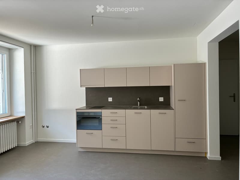 Modern kitchen with light-colored cabinets, stainless steel sink, oven, and built-in appliances.