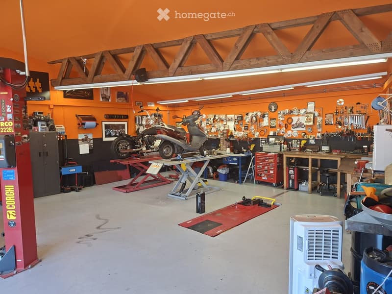A well-organized garage with a motorcycle on a lift, various tools and equipment neatly arranged, and a vibrant orange color scheme.