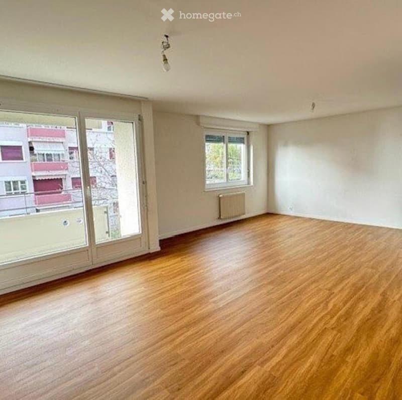 Empty room with wooden flooring, large glass sliding doors, and a radiator. No furniture or equipment present.