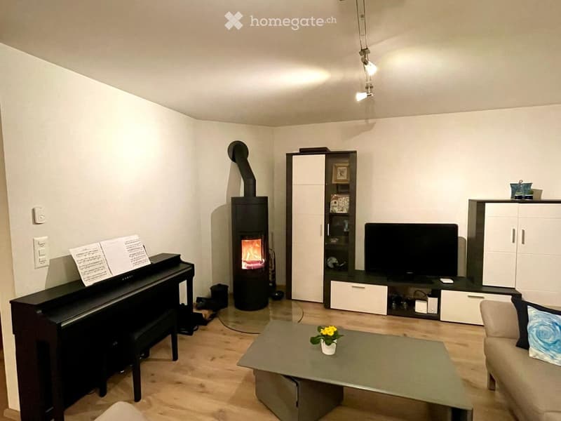 Modern living room with a fireplace, piano, sofa, coffee table, and television.