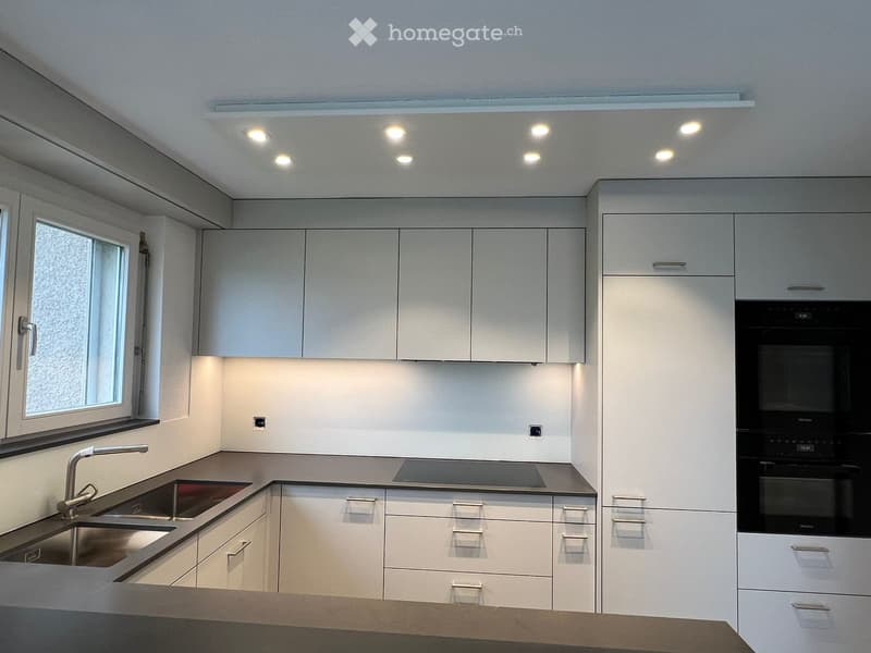 Modern kitchen with white cabinets, stainless steel sink, and built-in oven.