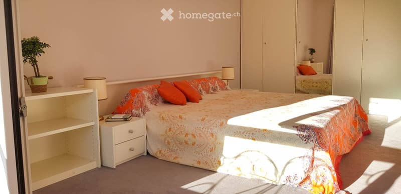 Bedroom with bed, nightstands, shelves, lamps, plants, and a mirror.