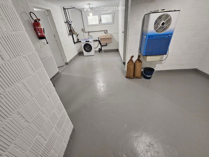 Utility corridor with white brick walls, a washing machine, a sink, a fire extinguisher, and an air conditioning unit.