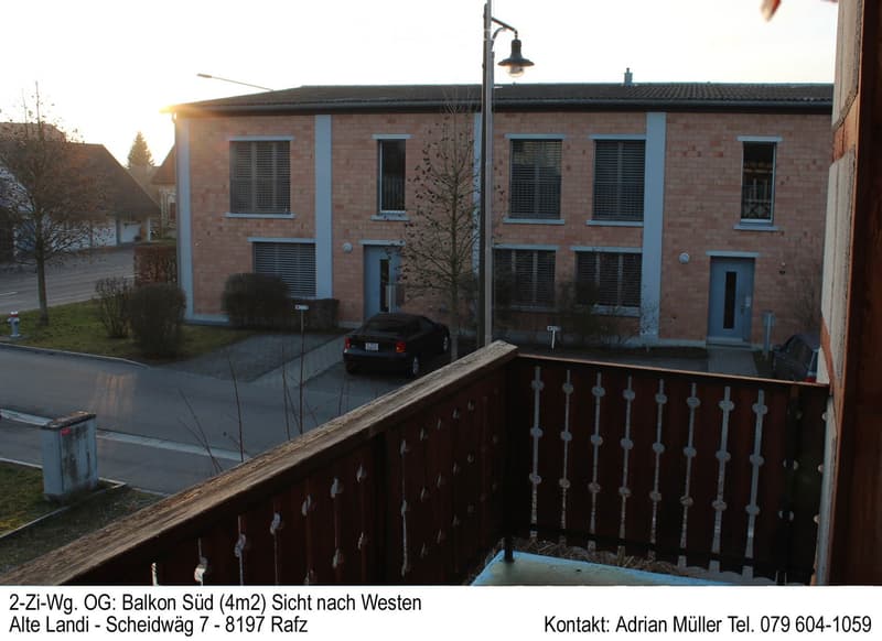 Balcony overlooking a residential street with a two-story brick house, parked cars, and street lighting visible.