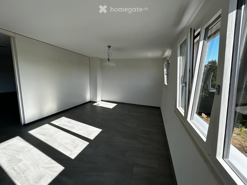 Empty hallway with dark tiled floor, white walls, and large windows on one side allowing natural light to enter.