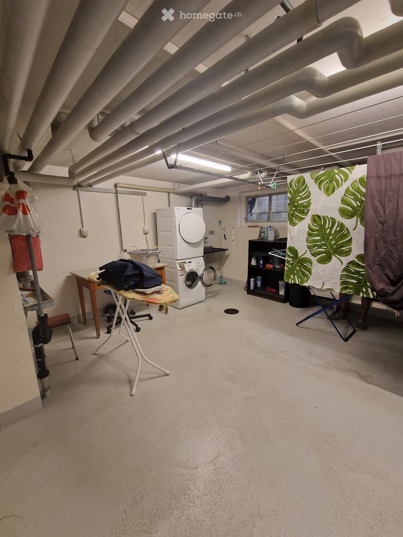 Laundry room with washing machine, table, chair, shelf, and basket.