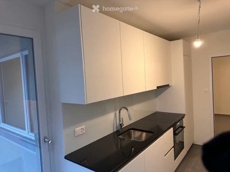 Modern kitchen with white cabinets, black countertop, and stainless steel sink.