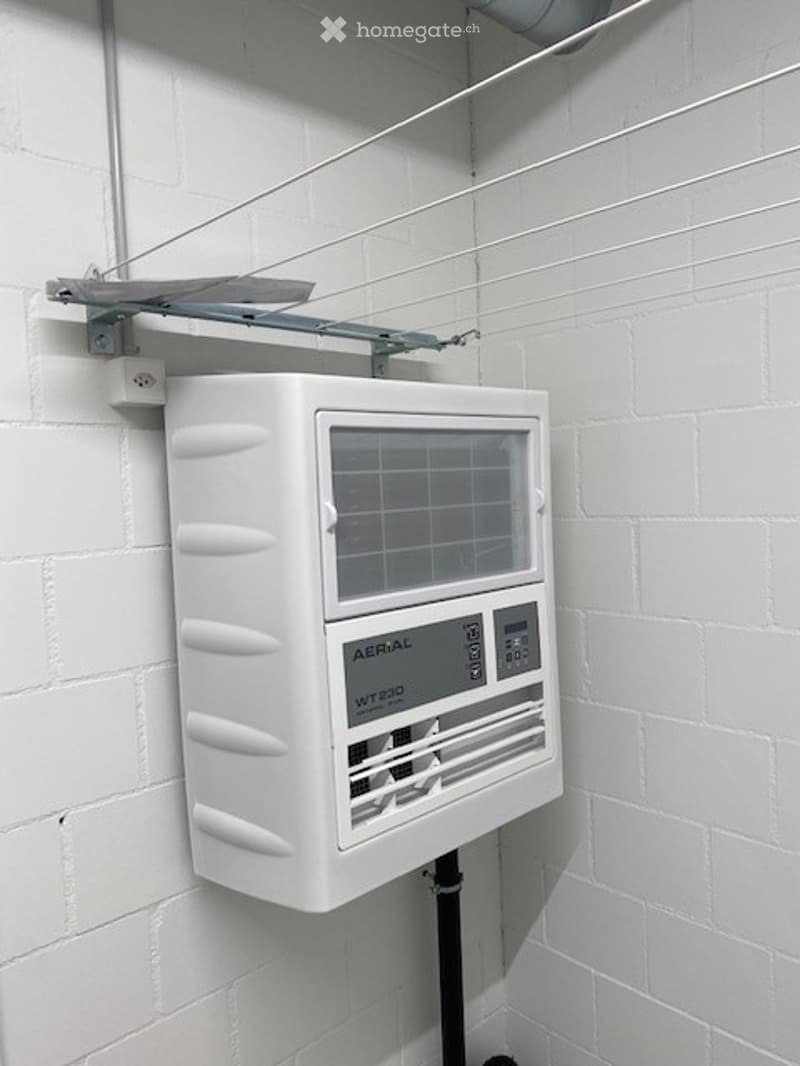A white wall-mounted air conditioning unit labeled "AERIAL WT200" is installed on a white brick wall, featuring a digital display and control buttons.