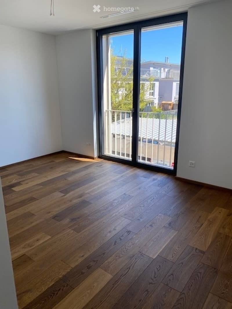Empty room with wooden flooring and large sliding glass doors leading to a balcony.