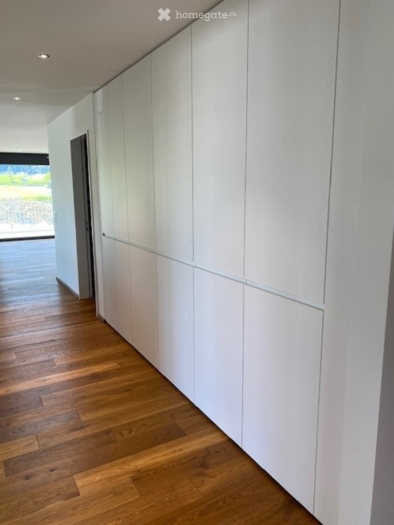Empty room with white built-in wardrobes and wooden flooring.