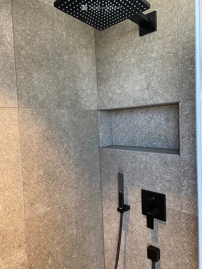 Modern shower area with a sleek black shower head, built-in shelves, and a contemporary control panel.