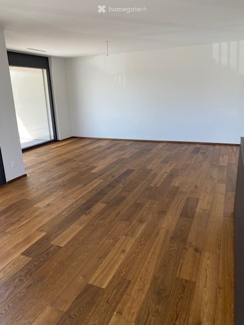 Completely empty room with wooden flooring and white walls. No furniture or equipment.