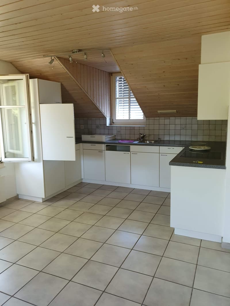 Bright kitchen with white cabinets, tiled floor, and a window with blinds. Features a sink, faucet, and a dishwasher.