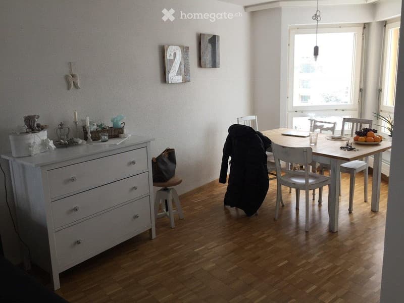 Wooden floor, white walls, white cabinet, dining table, dining chairs, windows, plates, fruits, lamp