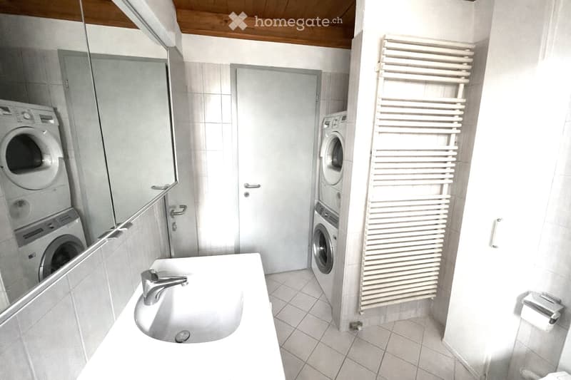 white sink, white tiles, white washing machine, white dryer, white towel rack, mirror, toilet