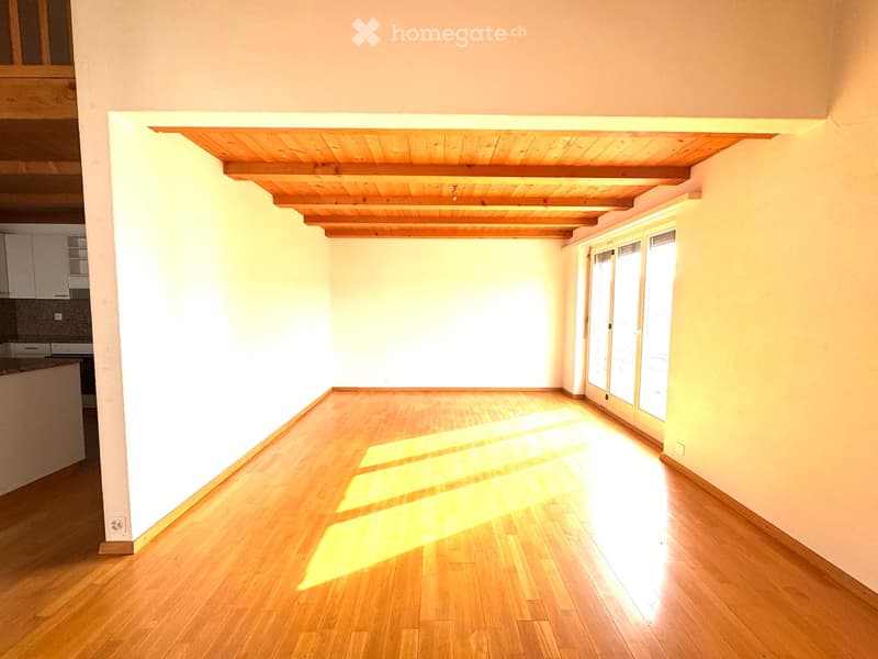 empty room, wooden floor, wooden ceiling, large windows, kitchen visible in background