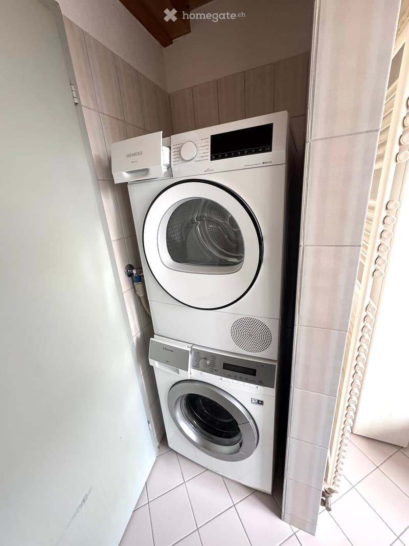 Stacked washing machine and dryer in a corner of a room