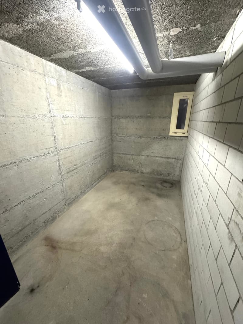 Empty room, concrete walls, concrete floor, small window, pipe on ceiling