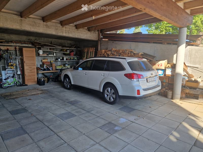 {"type": "Garage", "objects": ["car", "shelves", "tools", "wood stack", "bicycle"], "description": "Garage with tiled floor, white SUV parked inside, shelves with tools and supplies, wood stack, bicycle, and covered wooden ceiling.", "visible_features": [