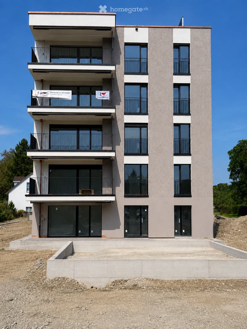 Modern two-story residential building with balconies, large windows, and a raised ground floor.