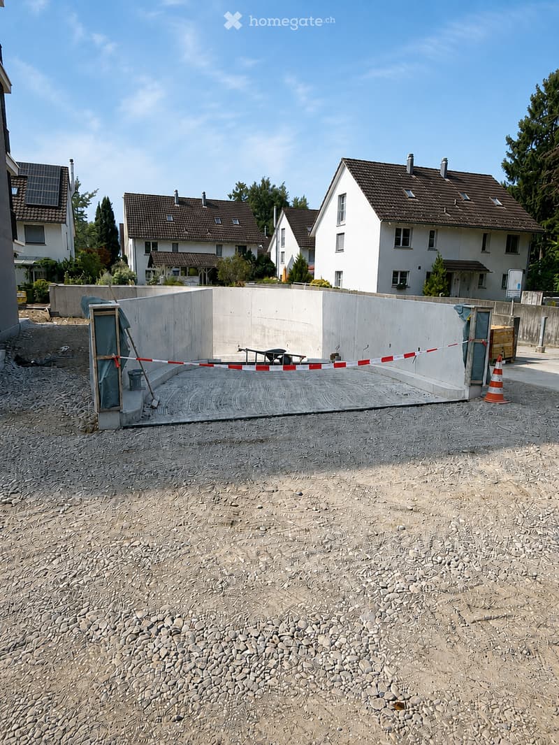 Construction site with a raised ground floor, concrete walls, and a fenced-off area with construction materials and traffic cones.