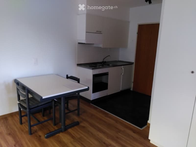 A compact kitchen area with a small table and chairs, a sink, and an oven.