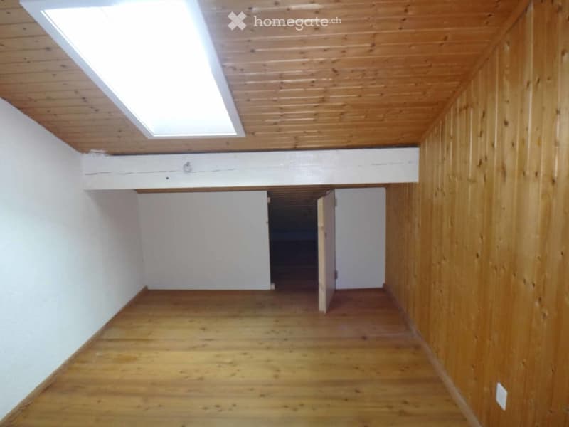 Empty room with wooden flooring, white walls, and a skylight window in the ceiling. No furniture or equipment is present.