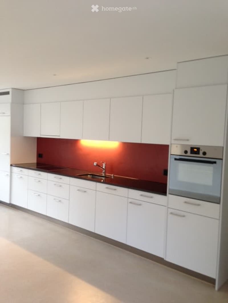 Modern kitchen with white cabinets, dark countertops, and built-in appliances including a sink and oven.