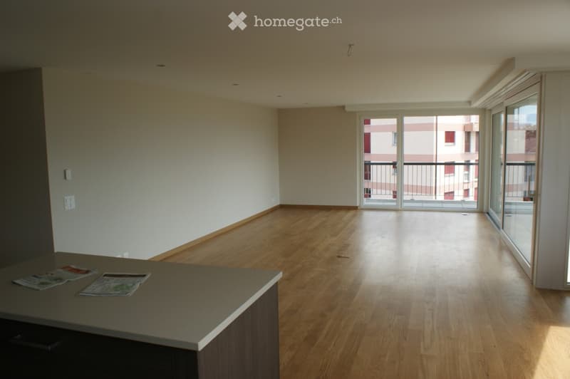 Empty room with wooden flooring, large windows, and a balcony access. No furniture or equipment present.
