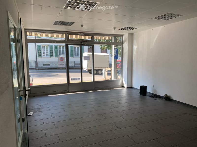 Empty room with tiled floor, white walls, and large glass doors leading to the outside. No furniture or equipment present.