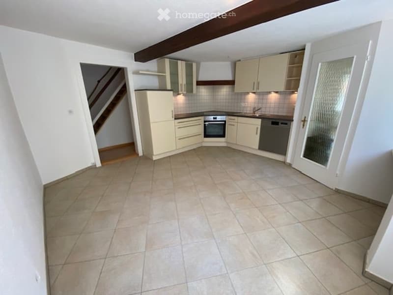 Modern kitchen with light-colored cabinets, tiled floor, and built-in appliances including an oven, sink, and dishwasher.