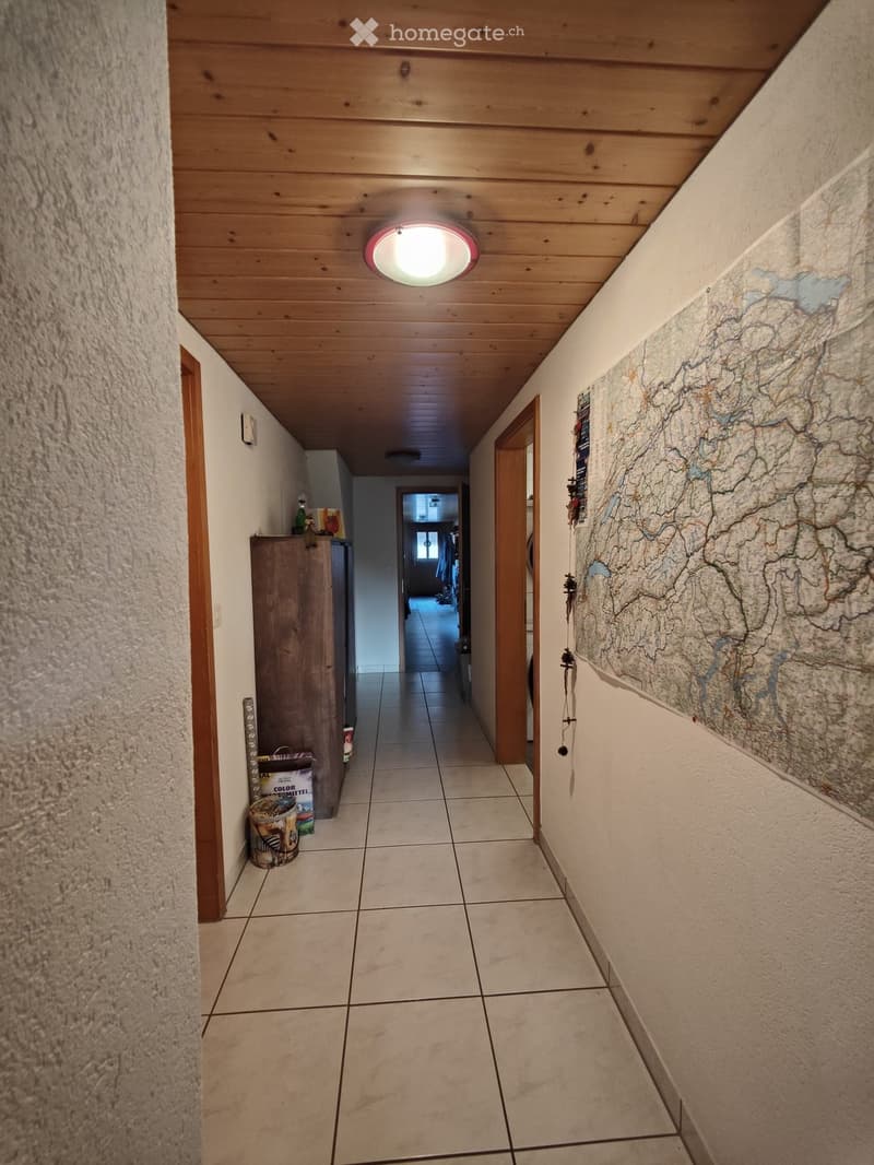 Hallway with wooden ceiling, tiled floor, and a large map on the wall. There are several doors and a small cabinet with items on top.
