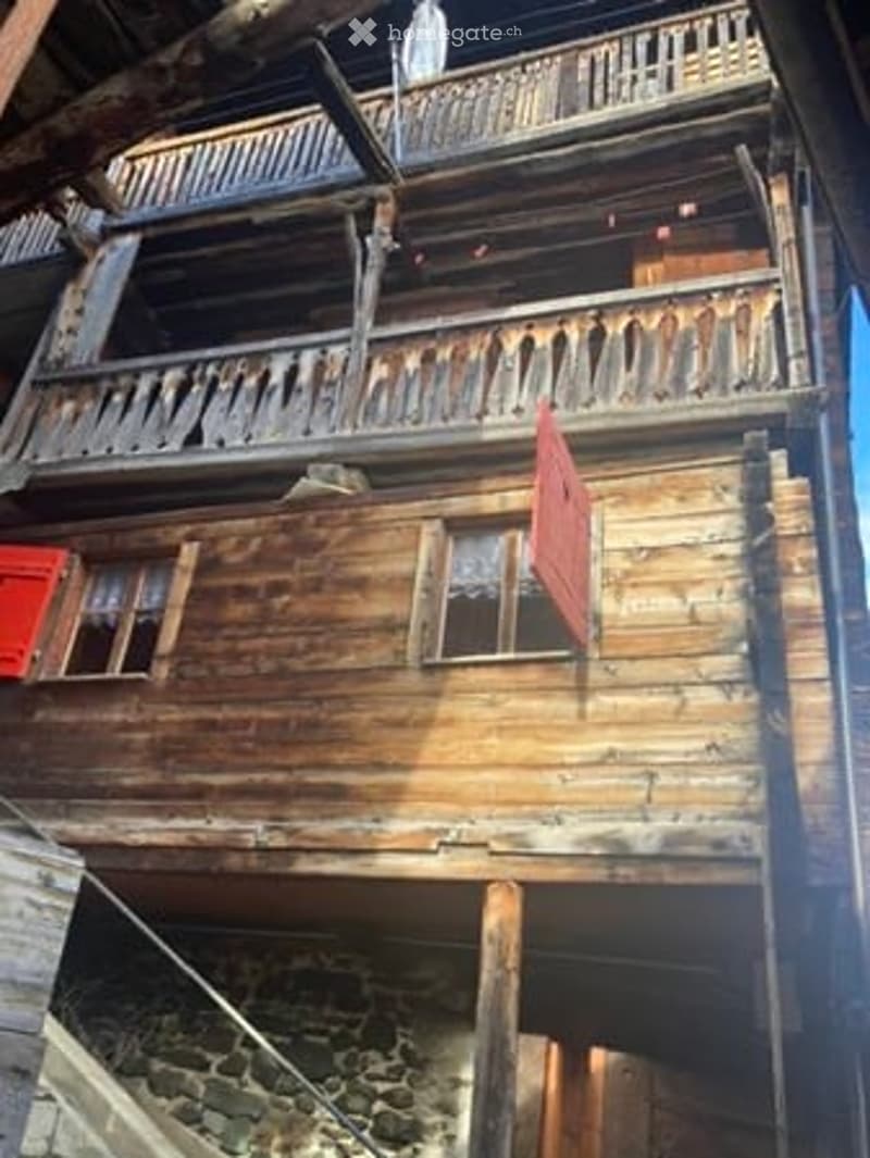 Traditional wooden chalet with exposed beams, wooden balconies, and red shutters.