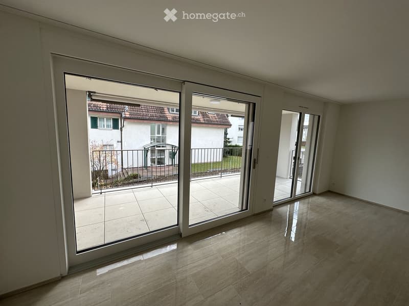 Empty room with large sliding glass doors leading to a balcony area, tiled floor, and white walls.