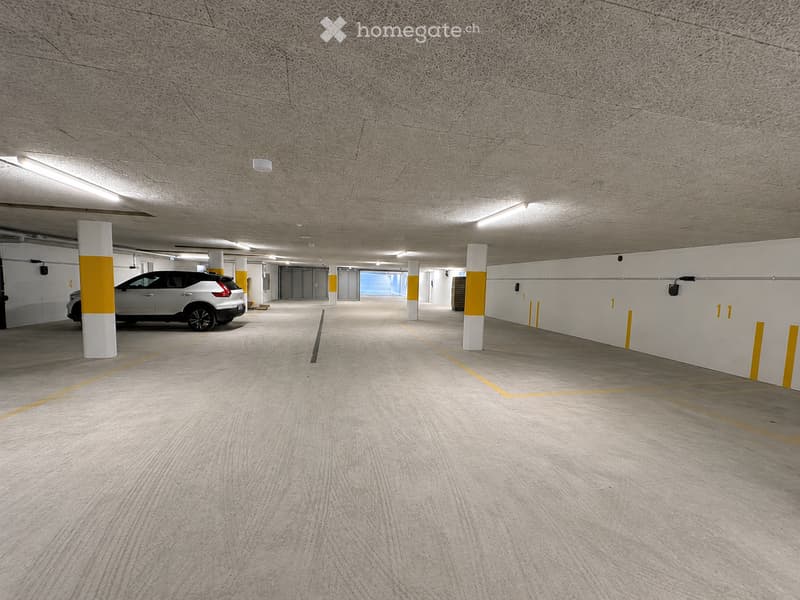 Modern underground parking area with clean, organized space, marked parking spots, and a single parked car.