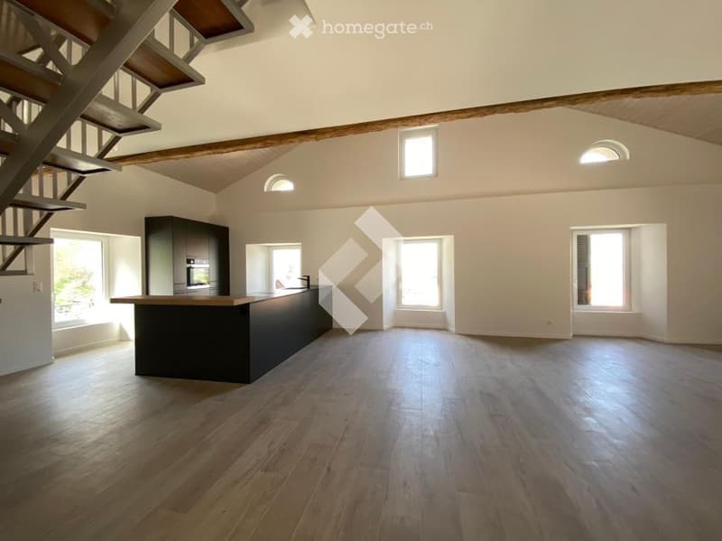 Open-plan space with wooden flooring, kitchen island, built-in oven, and cabinetry. Natural light from multiple windows and skylights.