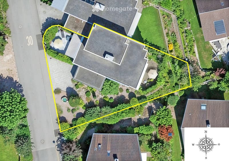 Aerial view of a residential property with a large house, surrounding greenery, a swimming pool, and neighboring houses.