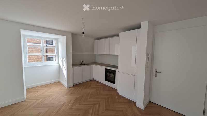 modern kitchen with white cabinets, wooden floor, window, sink, oven, and a lamp