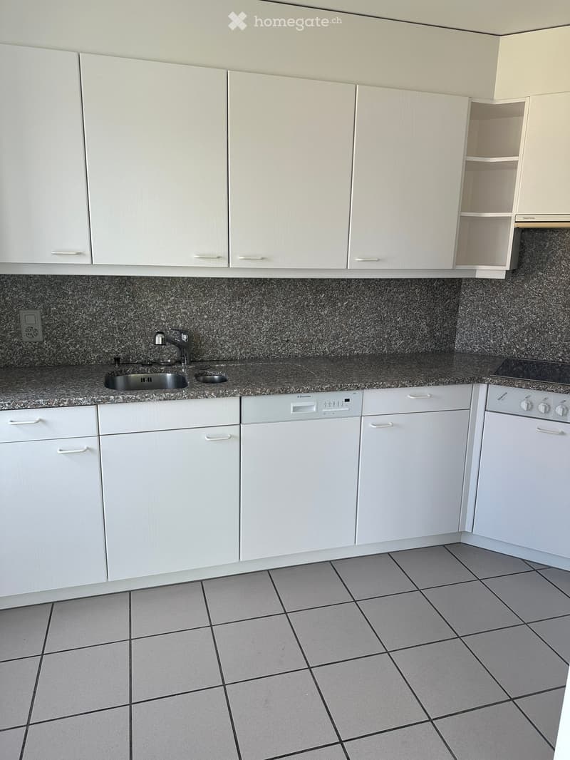 Modern kitchen with white cabinets, granite countertop, sink, dishwasher, and oven.