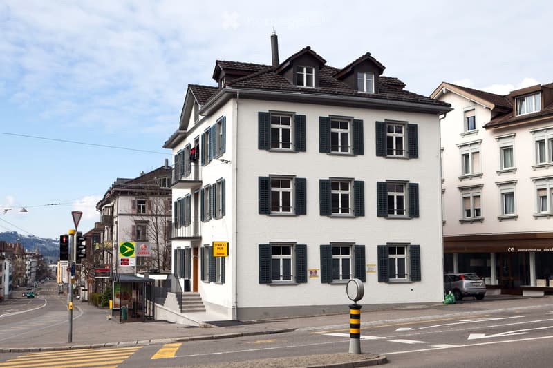 white exterior, brown roof, many windows, stairs leading to entrance, ground floor balcony