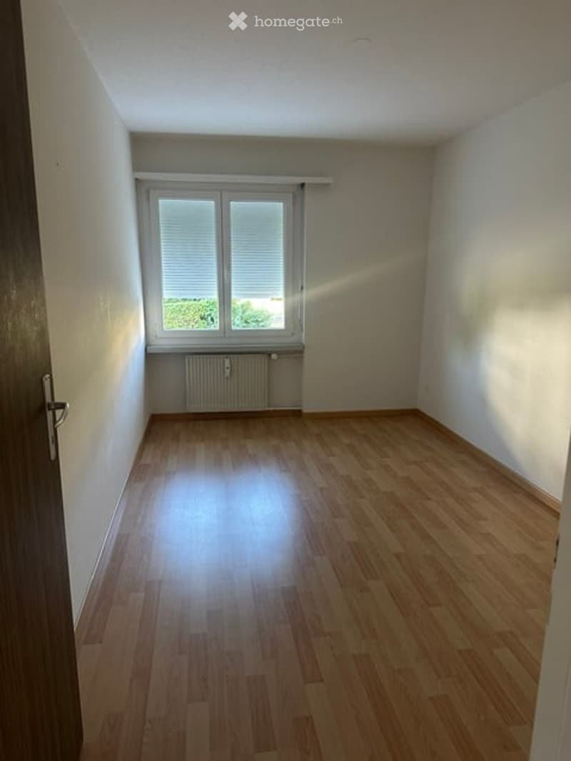 Empty room with wooden flooring, white walls, and a window with blinds. No furniture or equipment present.