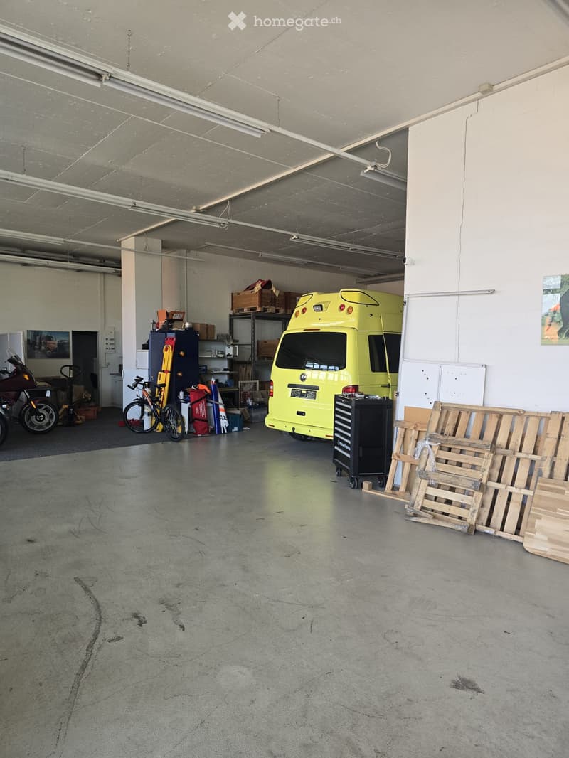 {"type": "Garage", "objects": ["motorcycle", "bicycle", "van", "toolbox", "pallets"], "description": "A spacious garage with a concrete floor, fluorescent lighting, and various stored items including a yellow van, a motorcycle, a bicycle, a toolbox, and w